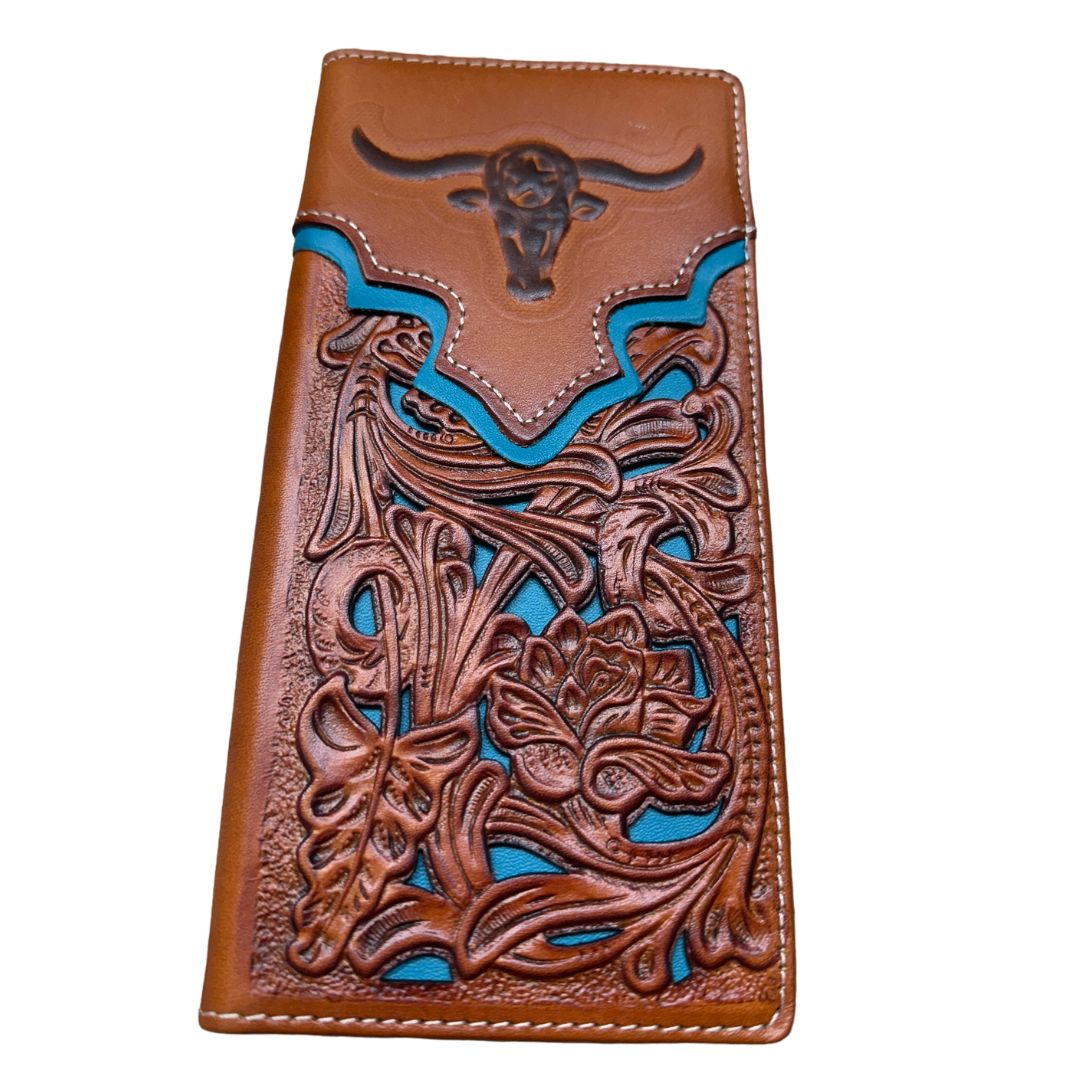 A **Western Stakes Floral Long Wallet Longhorn Teal Accent** featuring intricate embossed floral patterns and turquoise accents. The top flap is decorated with a raised bull skull motif, making it a perfect cowboy gift. Crafted from high quality leather, the edges are stitched with white thread, adding a neat finish to the artisanal design.