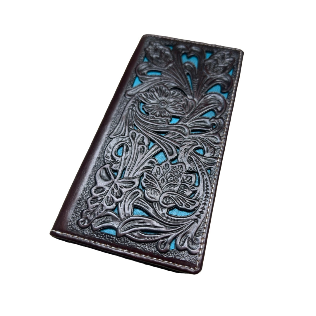 The **Western Stakes Floral Leather Long Wallet Coffee Teal** features an intricately designed leather exterior with a dark brown surface. This checkbook style wallet showcases an elaborate floral pattern, revealing a turquoise background peeking through the cut-out sections, giving it a unique and artistic look.