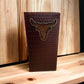 A handmade, vertically-oriented Longhorn Long Wallet Brown Basketweave W/ Cow Hair by Western Stakes is displayed on a wooden surface. The soft leather wallet features a woven pattern and an embossed, hand-tooled longhorn design on the front. The background consists of wooden planks.