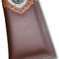 A brown leather wallet featuring a silver emblem and studs on a tan and gray leather patch at the top. The emblem depicts a stylized bull's head, reminiscent of a Longhorn. This western accessory also boasts visible stitching along the edges. Introducing the Longhorn Long Wallet Brown With Cowhair & Concho by Western Stakes.