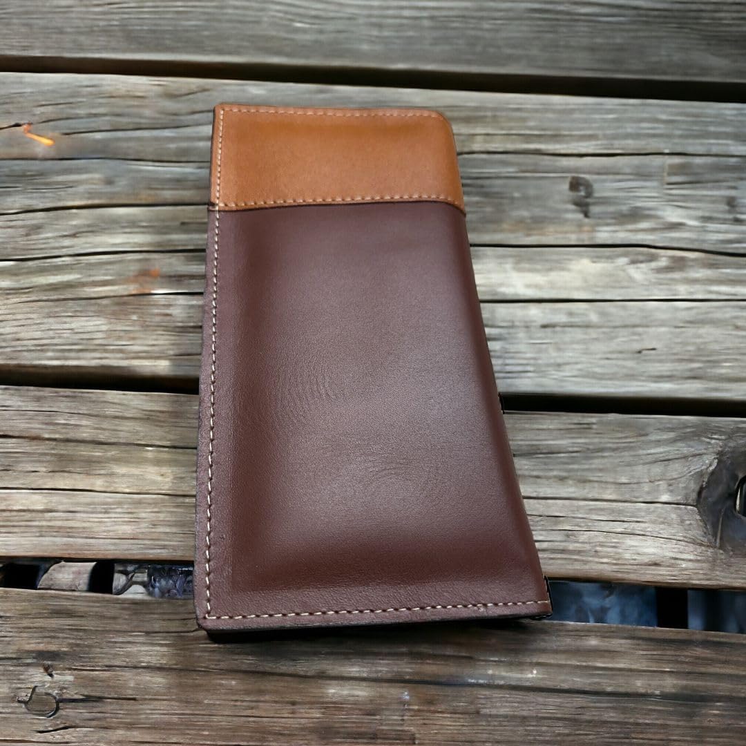 A brown leather wallet with a lighter tan section at the top, often seen as a classic western accessory, is placed on a weathered wooden surface. The Western Stakes Longhorn Long Wallet Brown With Cowhair & Concho appears to be well-crafted and closed, showcasing its exterior design.