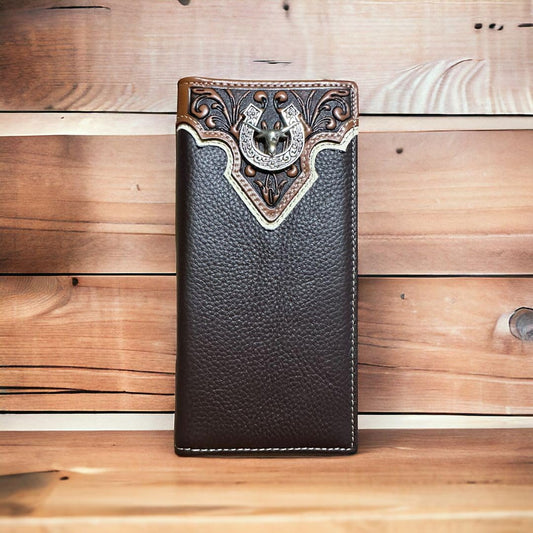 A brown leather wallet with intricate stitching and a silver anchor embellishment at the top center is displayed against a wooden background. The Western Stakes Men's Leather Long Wallet Longhorn Horseshoe Coffee features a textured finish and ornate detailing on the top section.