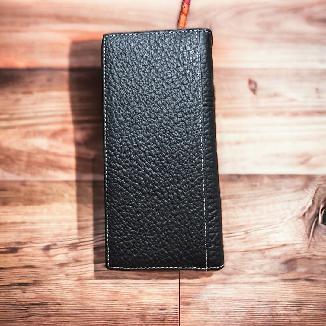 A rectangular, black leather long wallet with a pebbled texture is placed on a wooden surface. The spacious checkbook style *Horse Horseshoe Long Wallet Coffee Red Tint* from *Western Stakes* is closed, showcasing its stitched edges. The background consists of wooden planks in varying shades of brown.