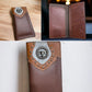 A stylish Western Stakes Longhorn Long Wallet Brown With Cowhair & Concho is shown in three angles. It features a leather patch with a circular emblem and stud details at the top, embodying a classic western accessory. One image highlights the exterior design, another shows the open interior with card slots, and a close-up displays the emblem and studs.