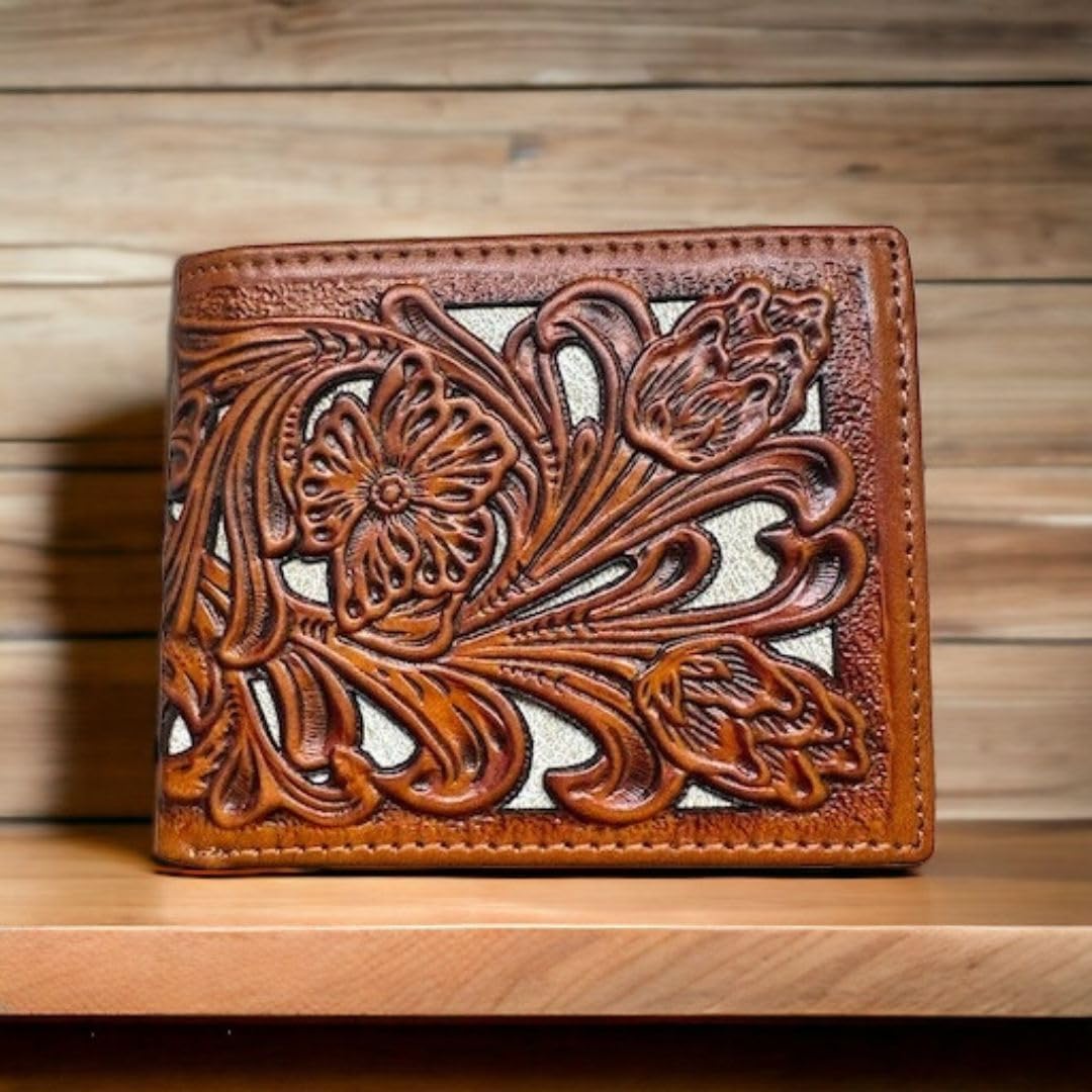 A Western Stakes Floral Leather Cowboy Wallet Brown & Teal featuring an intricate floral cutout design is displayed upright on a wooden surface. The background consists of wooden planks, giving the image a warm and rustic feel.