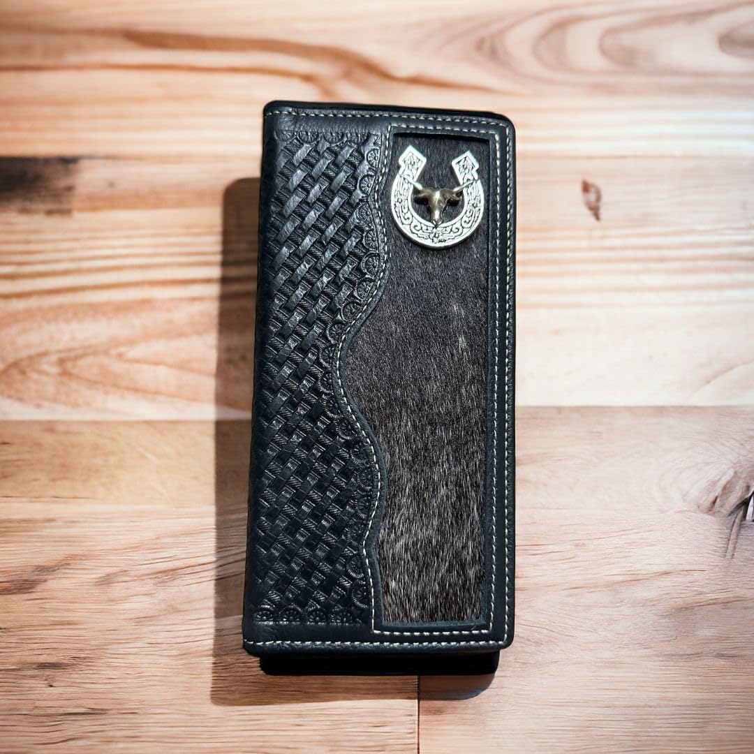 A Longhorn Long Wallet Black With Cowhair Basketweave by Western Stakes features a detailed silver horseshoe ornament at the top and is placed on a wooden surface.