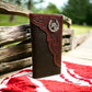 A Western Stakes Horse Horseshoe Long Wallet Coffee Red Tint placed on a red and white patterned cloth. The background features a wooden fence and lush greenery.