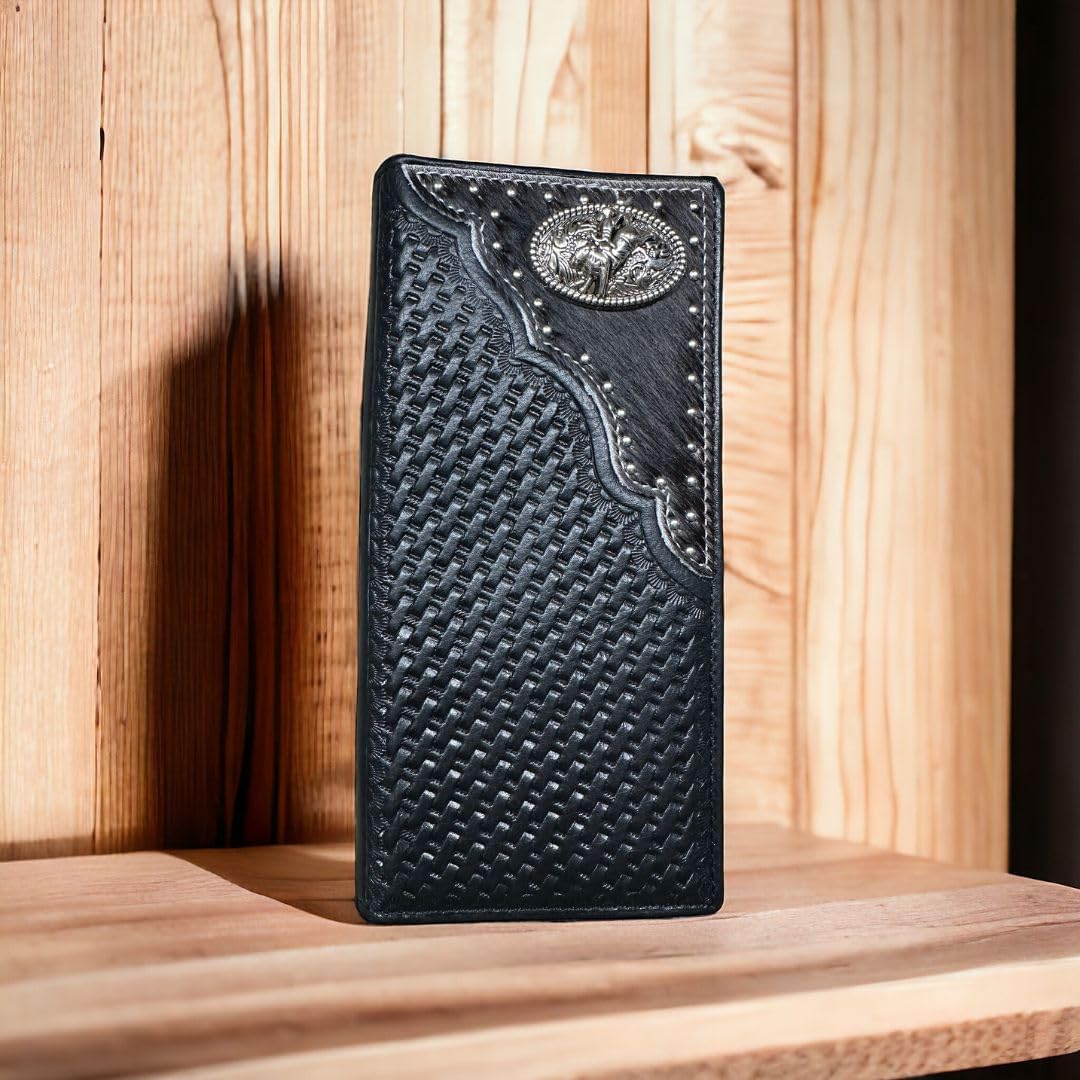 A black leather cowboy wallet with intricate woven patterns and decorative stitching is positioned upright on a wooden surface. The Western Stakes Bull Rider Long Wallet W Cowhair Basketweave also features a silver concho at the top corner. The background showcases a natural wood texture.