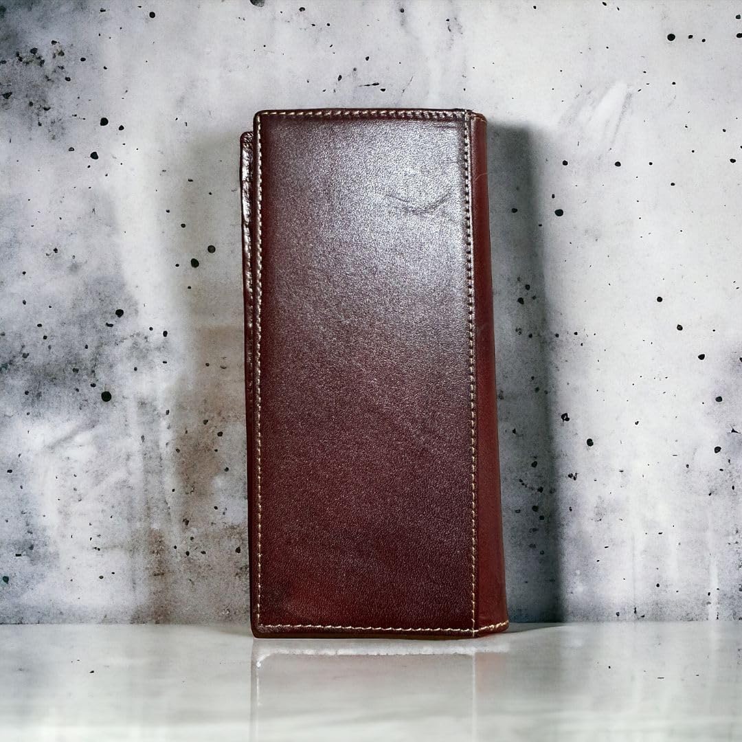 A closed, dark brown Western Stakes Longhorn Long Wallet Brown Basketweave W/ Cow Hair with a hand-tooled longhorn design stands upright against a textured, gray and white speckled background. The wallet's stitching and smooth texture are visible, adding a touch of sophistication to its appearance.