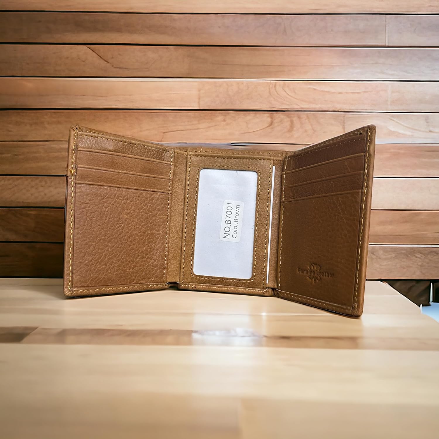 A Western Stakes Mens Brown Tri Fold Leather Wallet Longhorn Concho is open and standing on a wooden surface. It has multiple card slots, with one slot displaying a white card labeled "NO.78001 Cardman." The background consists of wooden panels, creating a warm and rustic appearance.