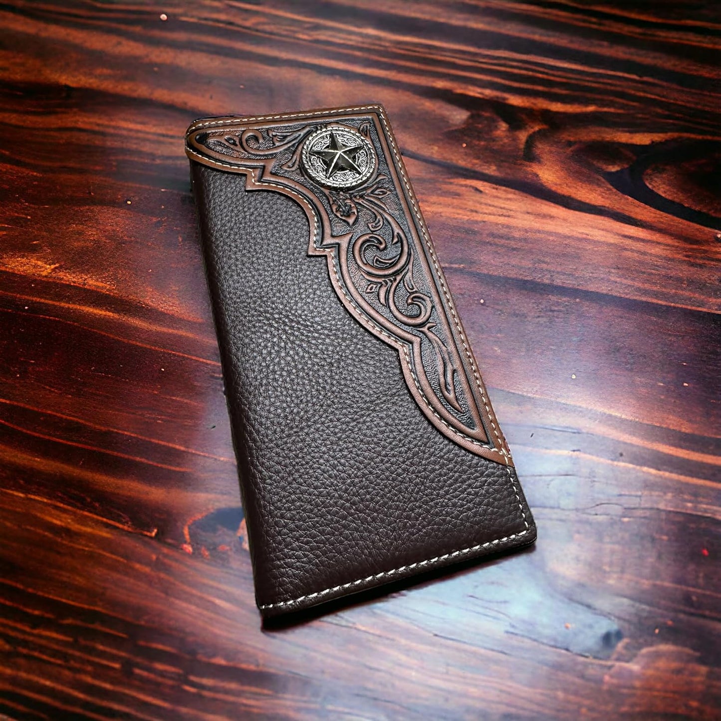 A dark brown men's leather wallet with an intricate embossed design on the upper left corner, featuring a star motif. This elegant gift for him is showcased on a polished wooden surface with a rich, reddish-brown grain. The Floral Long Wallet Coffee Star Concho by Western Stakes adds a touch of sophistication and style to any gentleman's accessory collection.